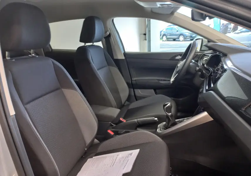 Vue intérieure côté gauche du Volkswagen Taigo 2025, montrant les sièges noirs et la console avec boîte manuelle.