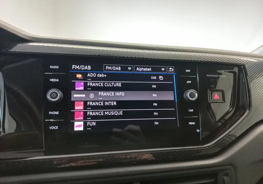 Écran tactile central du Volkswagen Taigo 2025 affichant les stations radio FM/DAB, entouré d’une finition noire brillante.