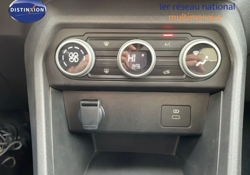 Gros plan sur la console centrale du Dacia Jogger kaki, montrant les commandes de climatisation et prises USB.