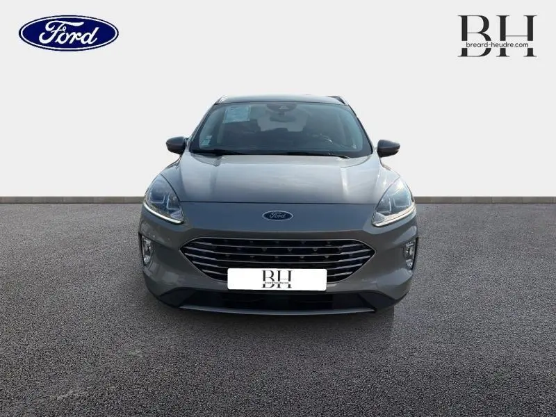 Vue frontale d'un Ford Kuga 2.0 EcoBlue gris Solar métallisé avec calandre large et phares LED allumés.