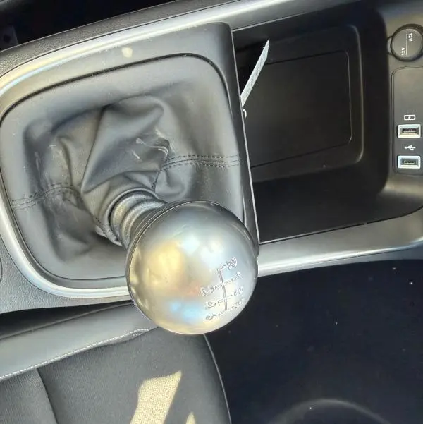 Gros plan sur le levier de vitesses manuel noir dans l'habitacle du Jeep Avenger blanc, avec ports USB et prise 12V visibles.