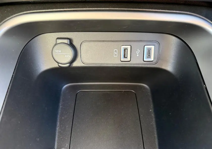 Prise USB et prise 12V en gros plan dans la console centrale du Jeep Avenger blanc, version 2025.