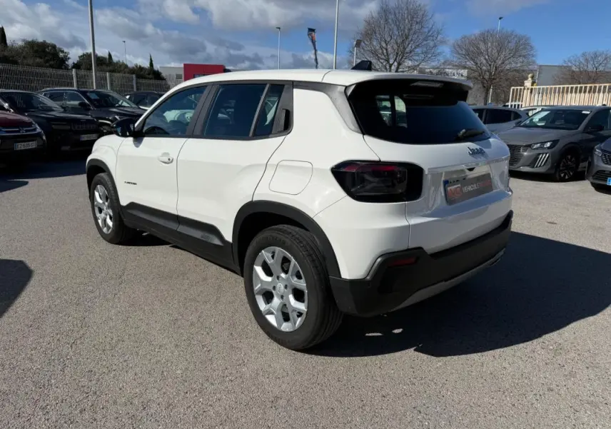 Jeep Avenger blanc en vue 3/4 arrière droit, avec jantes alliage 17 pouces et feux arrière noirs teintés.