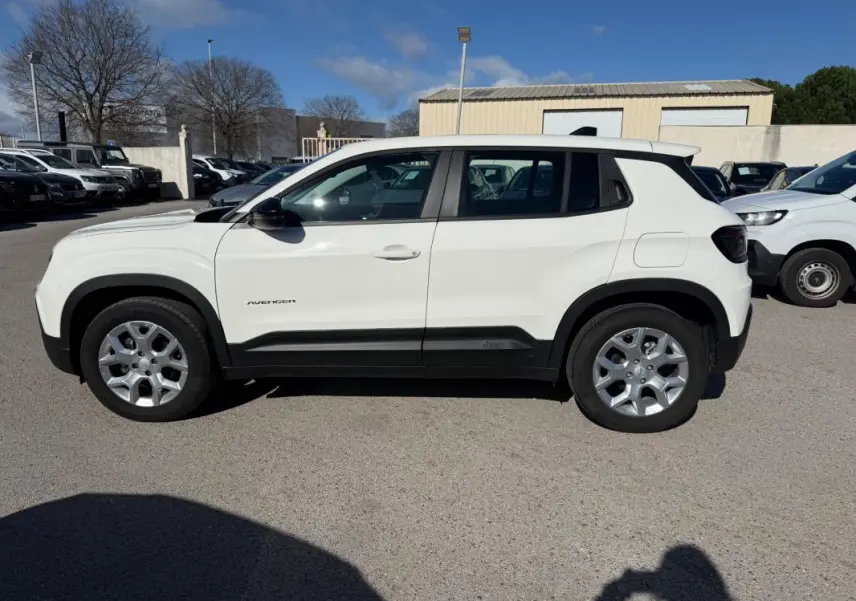 Profil côté gauche d'un Jeep Avenger blanc 2025 avec jantes alliage 17 pouces et protections noires sur bas de caisse.