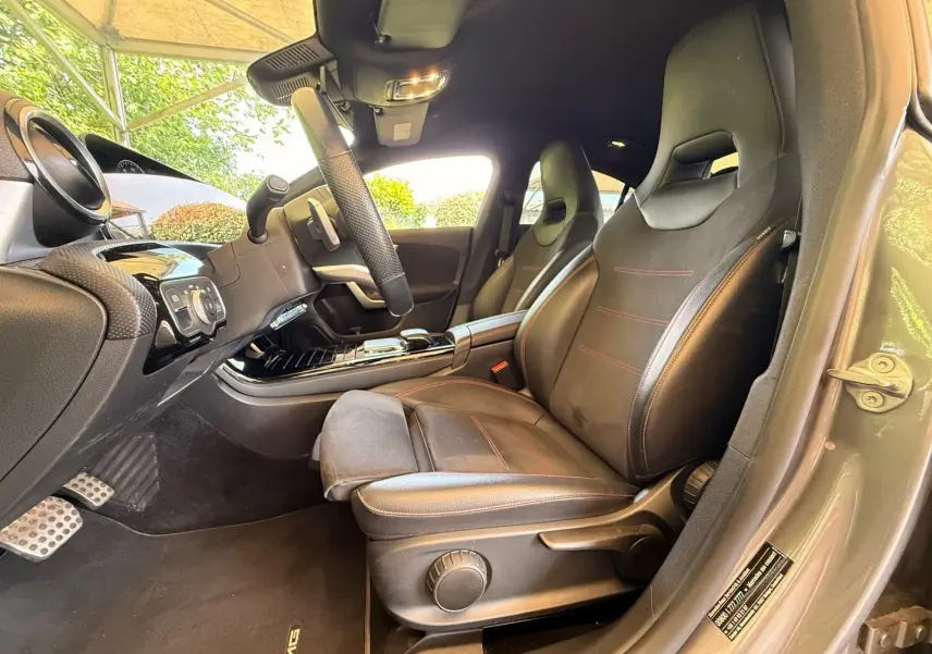 Intérieur côté conducteur de la Mercedes Classe CLA 180 D AMG Line 2019, sièges cuir noir avec surpiqûres rouges.