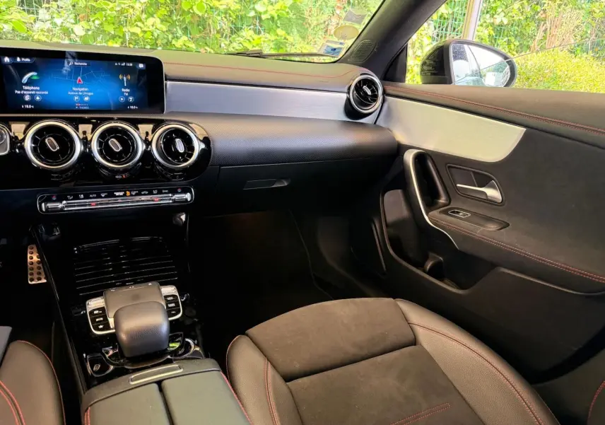Vue intérieure côté passager de la Mercedes Classe CLA 180 D AMG Line 2019, avec tableau de bord noir et surpiqûres rouges.