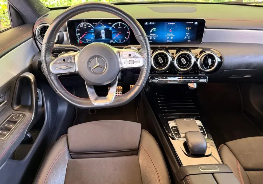 Vue intérieure avant de la Mercedes Classe CLA 180 D AMG Line 2019, volant cuir perforé et écran digital large.