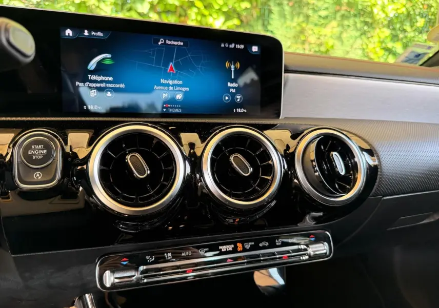 Vue rapprochée de la planche de bord de la Mercedes Classe CLA 180 D AMG Line 2019, avec écran tactile et aérateurs ronds noirs.