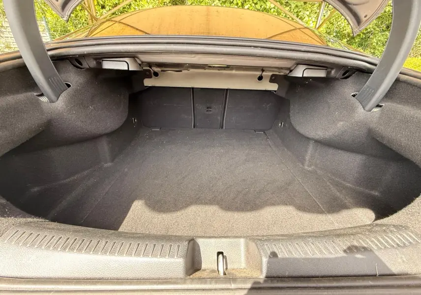 Coffre ouvert vu de l'arrière d'une Mercedes Classe CLA 180 D AMG Line gris montagne, espace de chargement vide et propre.