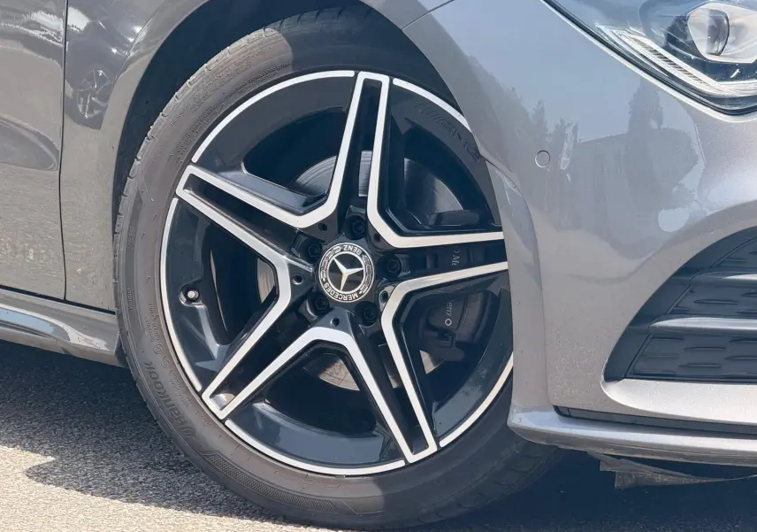Gros plan sur la roue avant gauche d'une Mercedes CLA 180 D AMG Line gris montagne avec jante étoile noire et argent.