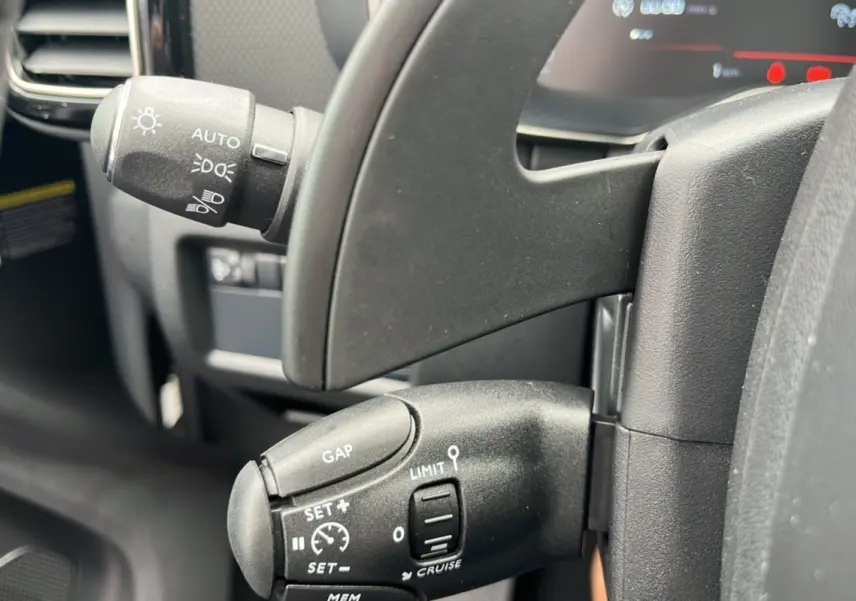 Gros plan sur les commandes au volant noir du Citroën C5 Aircross blanc, mettant en valeur les réglages du régulateur de vitesse.