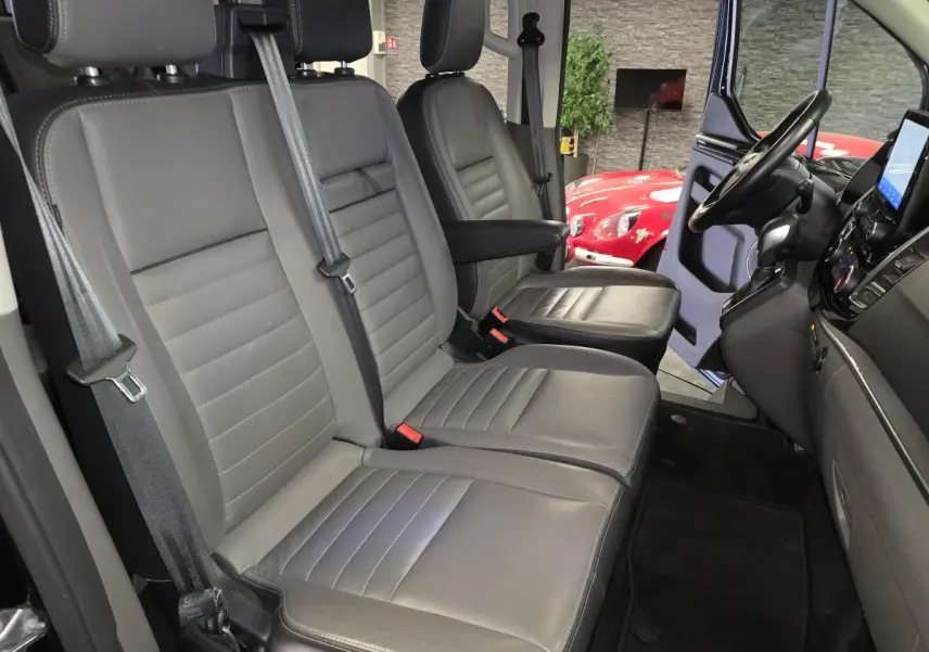 Vue intérieure côté conducteur du Ford Transit Fourgon Custom 2022, sièges cuir gris anthracite avec accoudoir.