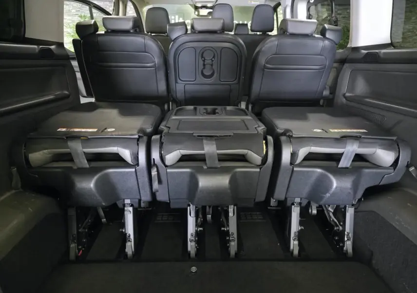 Vue arrière intérieure du Ford Transit Custom noir 2022, sièges de 2e rangée rabattus et modulables en cuir gris anthracite.