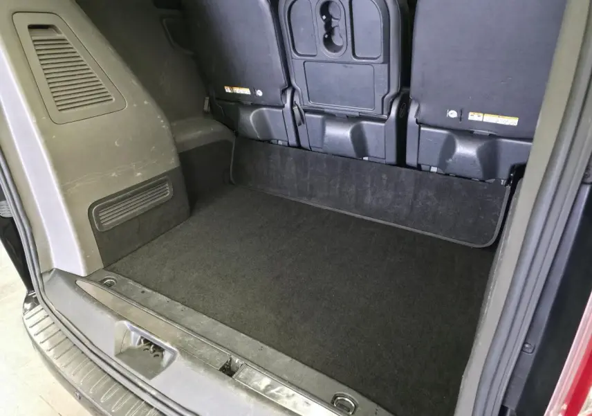Vue arrière de l'espace de chargement noir du Ford Transit Fourgon Custom avec sièges arrière rabattus.