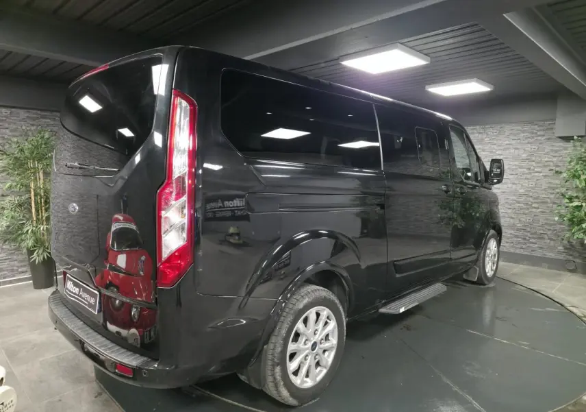 Ford Transit Fourgon Custom noir, vue 3/4 arrière droit, vitres teintées et jantes alliage 17 pouces visibles.