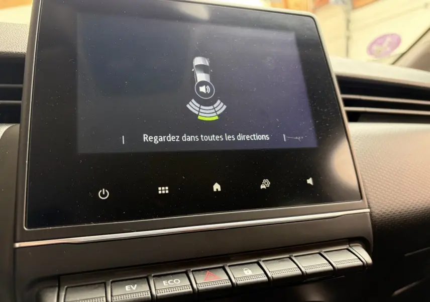 Écran tactile central affichant l'aide au stationnement dans l'habitacle de la Renault Clio Business E-Tech hybride blanc.