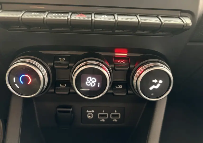 Gros plan sur les commandes de climatisation et ports USB de la Renault Clio Business E-Tech hybride blanc, tableau de bord central.