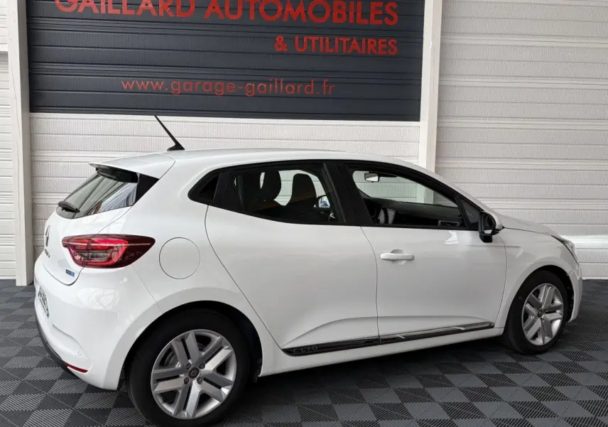 Renault Clio Business E-Tech hybride blanc vue de profil côté gauche, avec jantes alliage et logo Clio sur bas de porte.