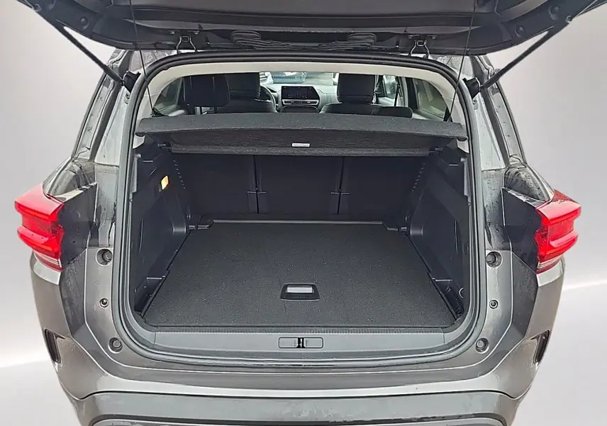 Coffre ouvert vu de l'arrière d'un Citroën C5 Aircross gris 2025 avec banquette arrière et tablette cache-bagages visibles.