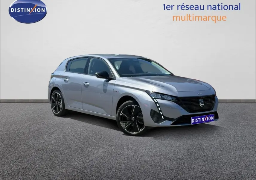 Peugeot 308 gris métallisé vue 3/4 avant droit, avec jantes noires et signature lumineuse LED verticale.