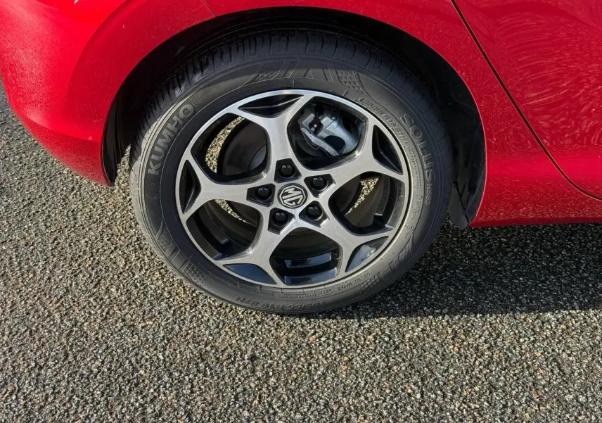 Gros plan sur la roue avant droite du MG3 1.5 Hybrid+ Luxury en rouge Diamond Red métallisé, jante alu à cinq branches.