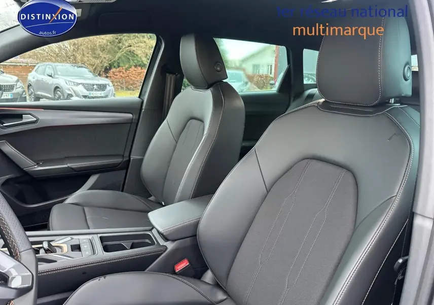 Vue intérieure avant de la CUPRA LEON ST 1.5 etsi hybrid 2025 avec sièges cuir gris et accoudoir central.
