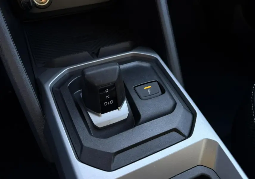 Gros plan sur la console centrale du Dacia Duster blanc Glacier 2025, montrant le levier de vitesses automatique et le bouton de parking.