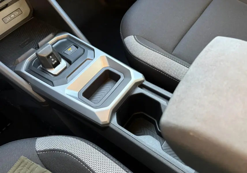 Vue rapprochée de la console centrale du Dacia Duster blanc glacier 2025 avec levier de vitesses automatique et accoudoir tissu.