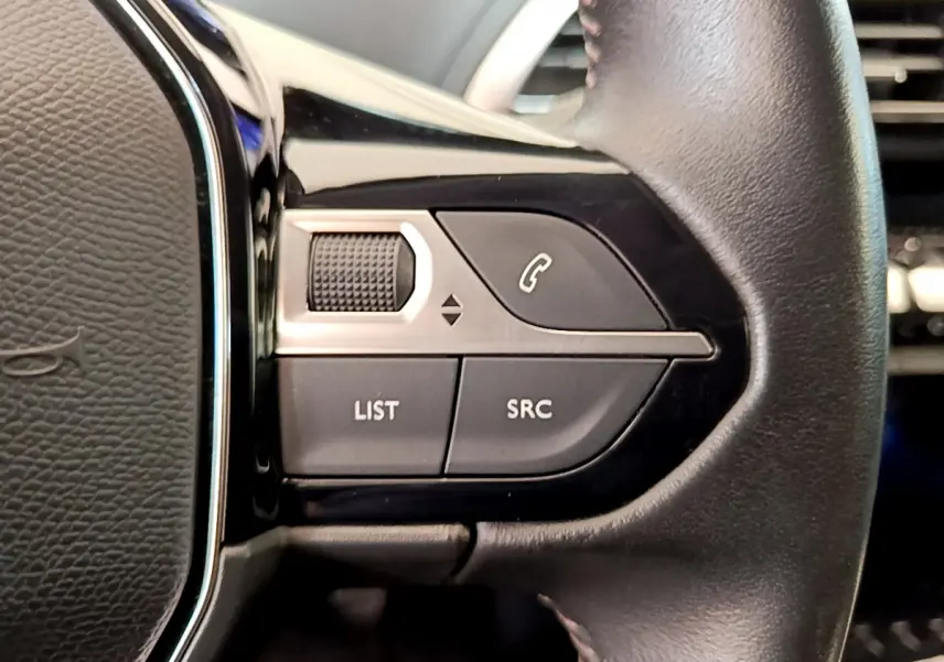 Gros plan sur les commandes gauche du volant cuir du Peugeot 3008 gris foncé, boutons LIST, SRC et téléphone.