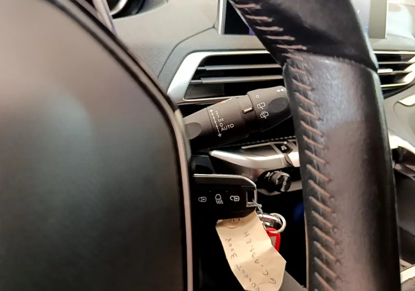 Gros plan sur le volant cuir et la commande d’essuie-glace du Peugeot 3008 gris foncé, version Puretech 130 S&S ACTIVE.