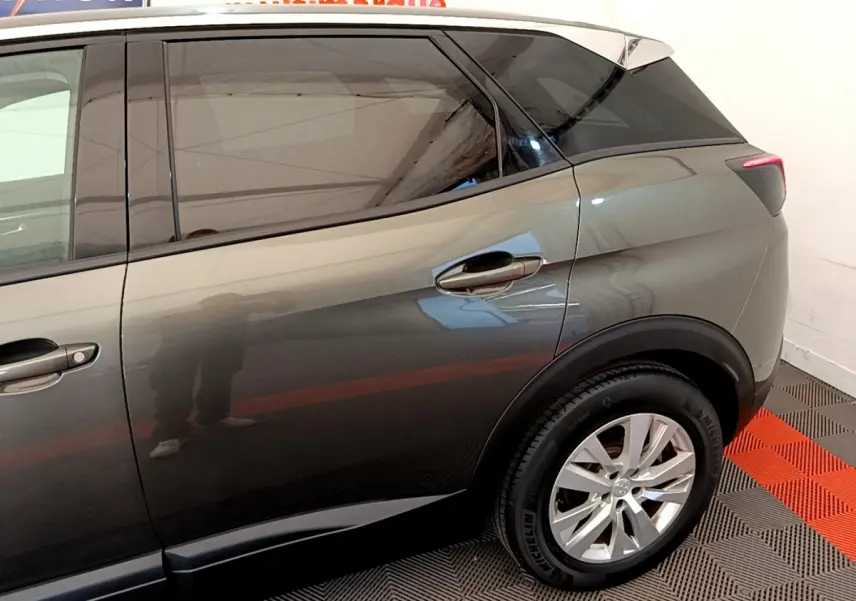 Vue latérale droite sur l'arrière d'un Peugeot 3008 gris foncé avec vitres teintées et jantes alliage.