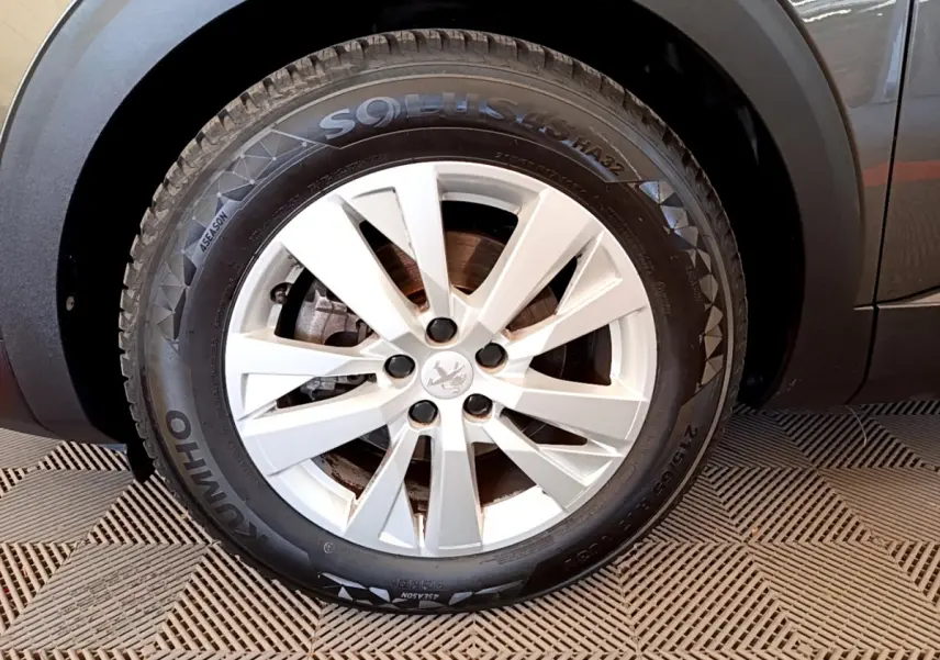 Gros plan sur la roue avant gauche du Peugeot 3008 gris foncé, mettant en valeur la jante alliage et le pneu Kumho.