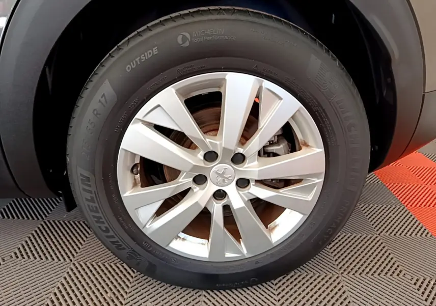 Gros plan sur la roue avant gauche du Peugeot 3008 gris foncé, avec jante alliage et pneu Michelin visible.