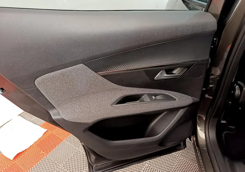 Vue intérieure côté gauche de la porte avant gris foncé du Peugeot 3008 avec garniture tissu et plastique noir.
