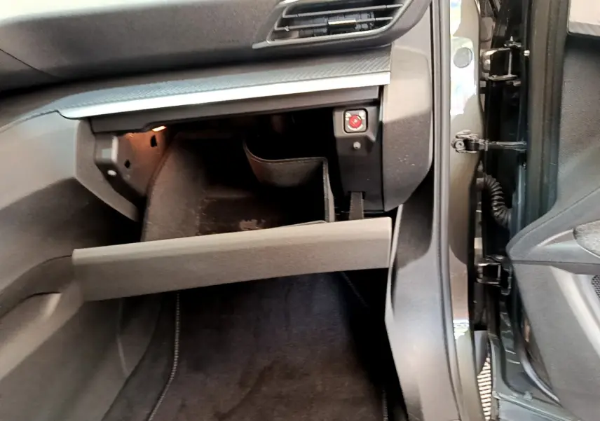Vue rapprochée de la boîte à gants ouverte côté passager du Peugeot 3008 gris foncé, intérieur noir.