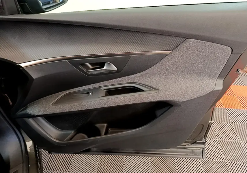 Vue intérieure du panneau de porte côté gauche du Peugeot 3008 gris foncé, avec poignée argentée et garniture textile.