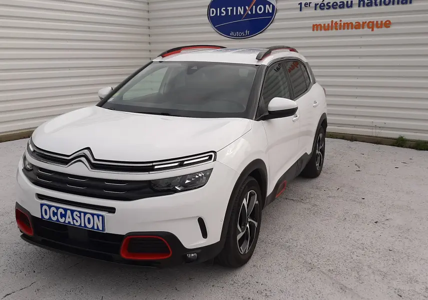 Citroën C5 Aircross blanc en 3/4 avant droit, avec détails rouges sur boucliers et jantes bicolores.