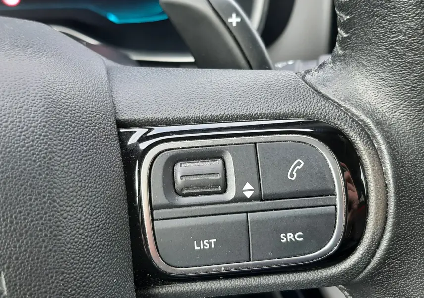 Gros plan sur les commandes noires du volant en cuir d’un Citroën C5 Aircross blanc, version BlueHDi 130ch Feel 2020.