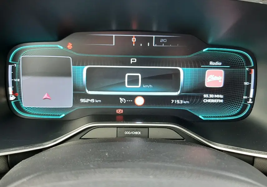 Vue rapprochée du tableau de bord numérique du Citroën C5 Aircross blanc, affichant la vitesse à 0 km/h et la radio allumée.