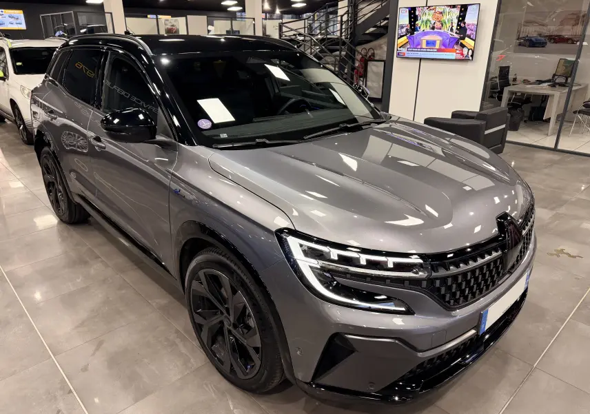 Renault Austral E-Tech gris schist avec toit noir, vue 3/4 avant droit mettant en valeur ses phares LED et jantes noires.
