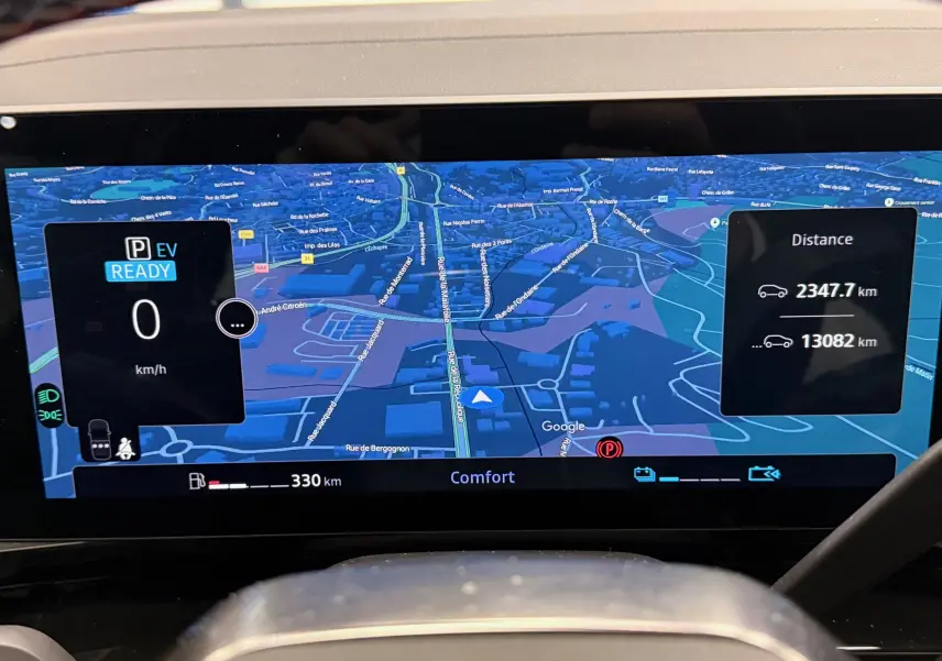 Affichage numérique du tableau de bord du Renault Austral E-Tech hybride, montrant la navigation et les distances parcourues.