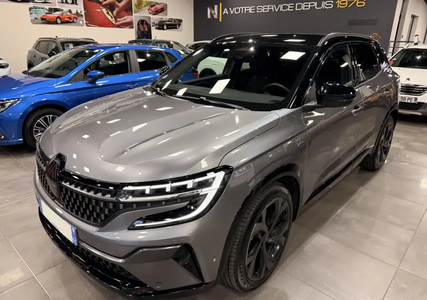 Renault Austral E-Tech hybride gris schist toit noir, vue 3/4 avant droit en intérieur showroom.