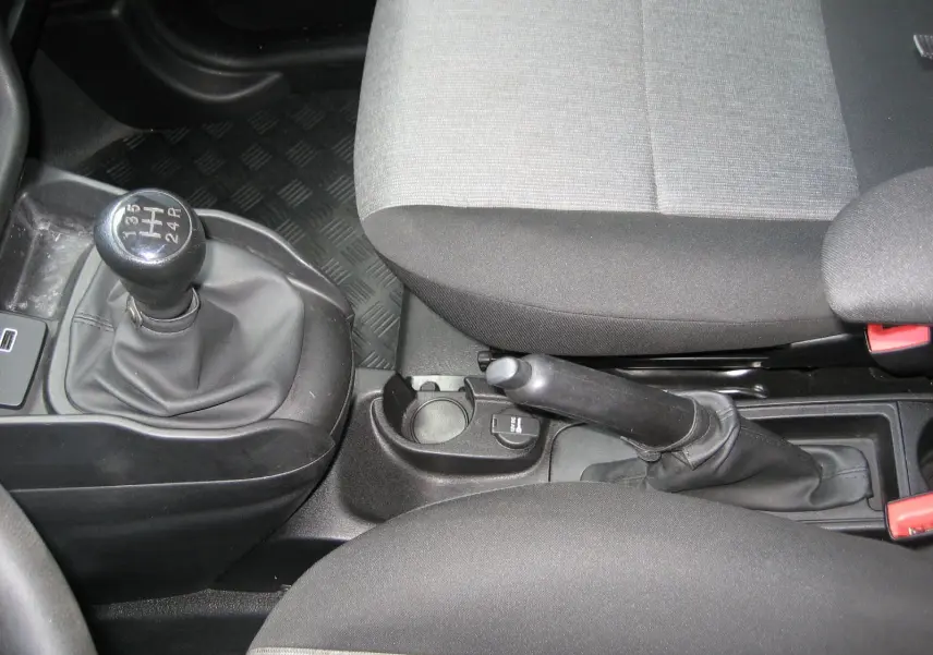 Vue rapprochée de la console centrale du Fiat Doblo Cargo blanc, montrant levier de vitesse manuel et frein à main.