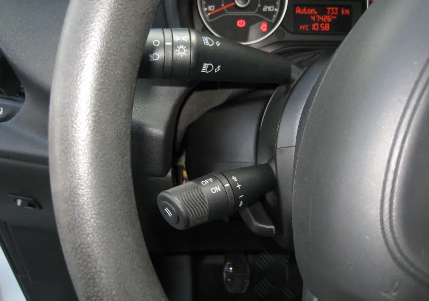 Gros plan sur le volant et le combiné d'instruments du Fiat Doblo Cargo blanc, avec affichage digital rouge et commandes au volant.