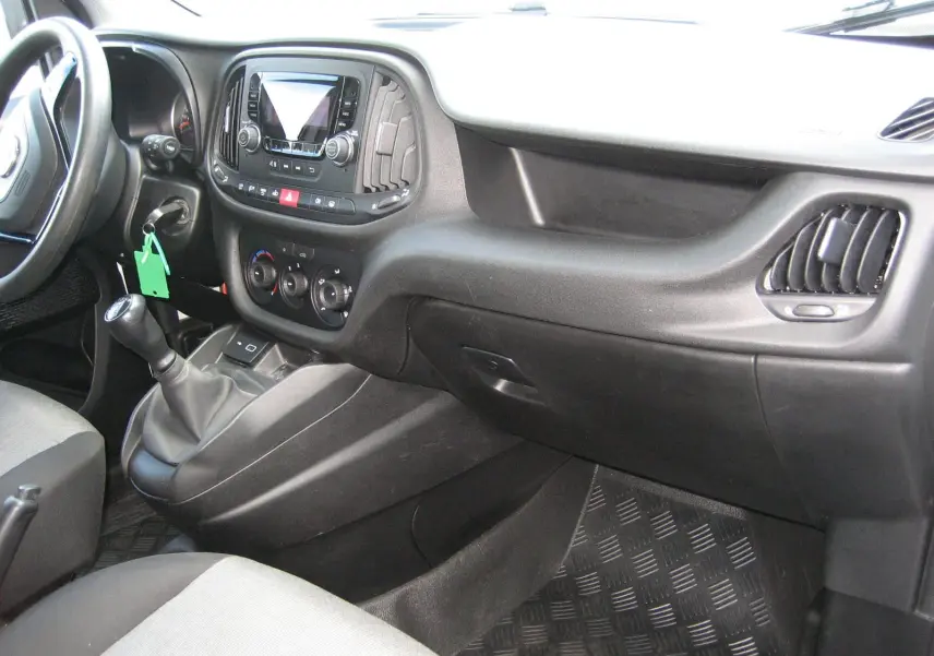 Vue intérieure côté passager du tableau de bord noir et gris du FIAT Doblo Cargo 2018 avec levier de vitesse manuel.