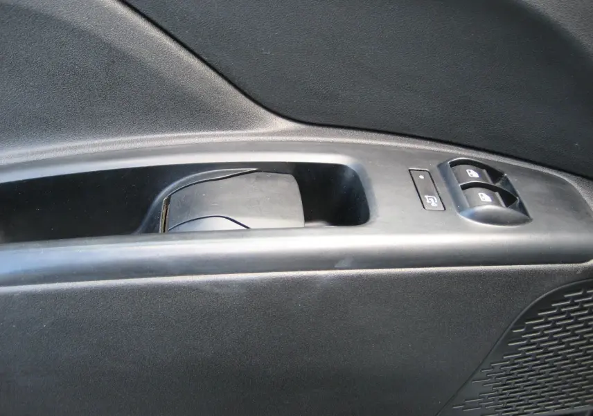 Gros plan sur la commande de lève-vitre et verrouillage sur la porte intérieure côté gauche du Fiat Doblo Cargo blanc.