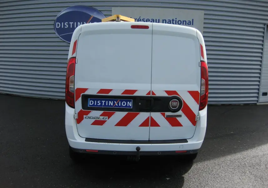 Vue arrière d'un FIAT Doblo Cargo blanc de 2018 avec marquages rouges réfléchissants et attelage visible.