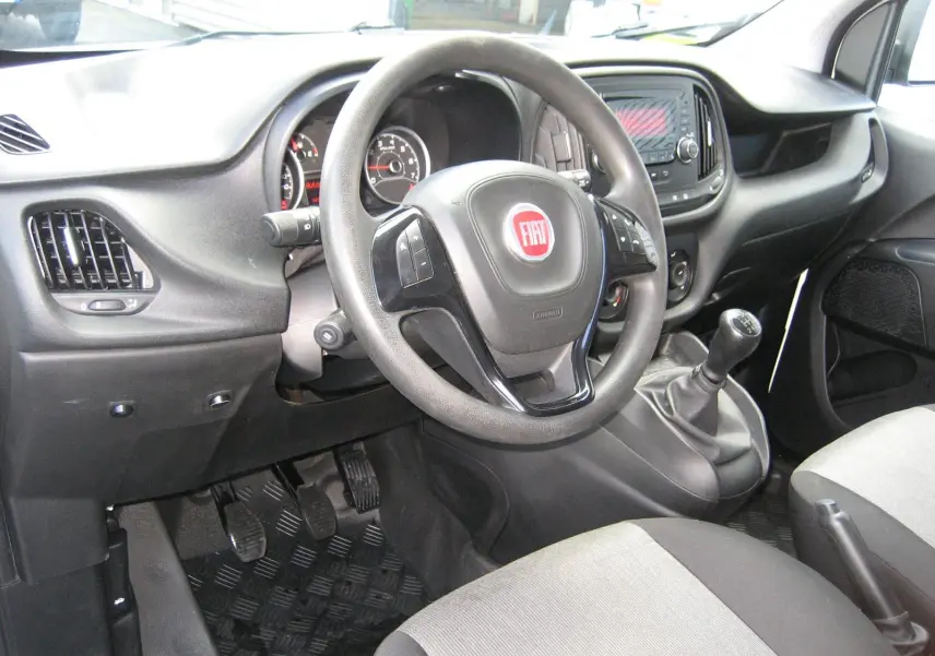Vue intérieure côté conducteur du Fiat Doblo Cargo 2018, volant multifonction et levier de vitesses manuel visibles.
