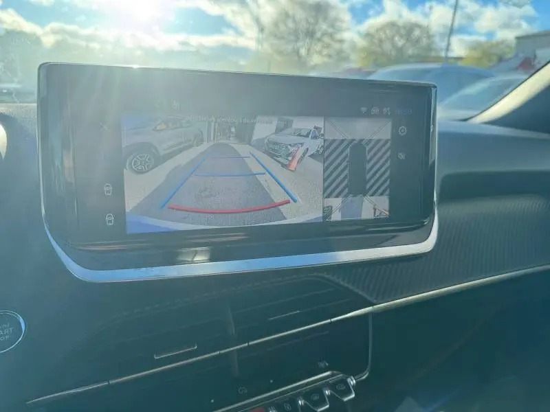 Écran tactile intérieur montrant la caméra de recul du Peugeot 2008 gris Hybrid 136 e-DCS6 Allure en plein jour.