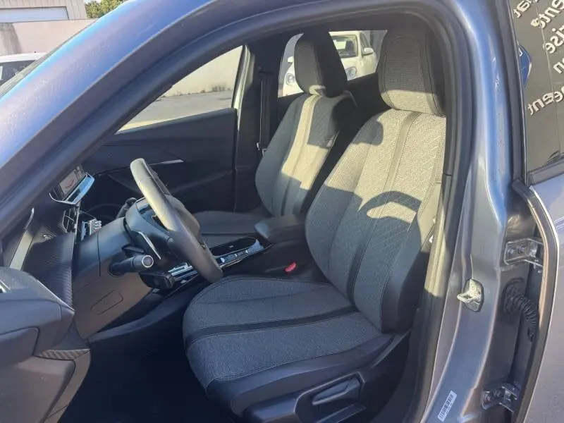 Vue intérieure côté conducteur du Peugeot 2008 Hybrid gris 2025, montrant les sièges avant et le tableau de bord moderne.